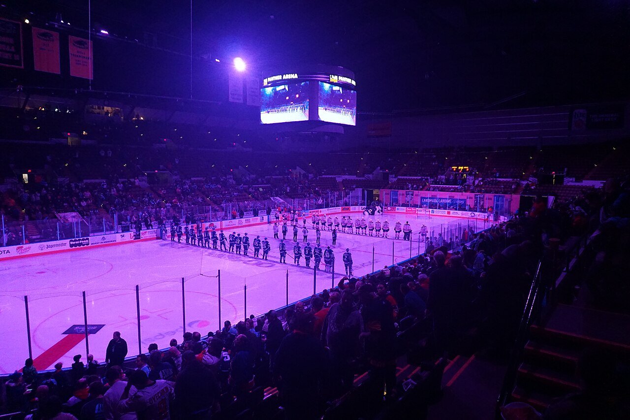 Hockey players line up on purple-lit ice during a Hockey Fights Cancer commemoration