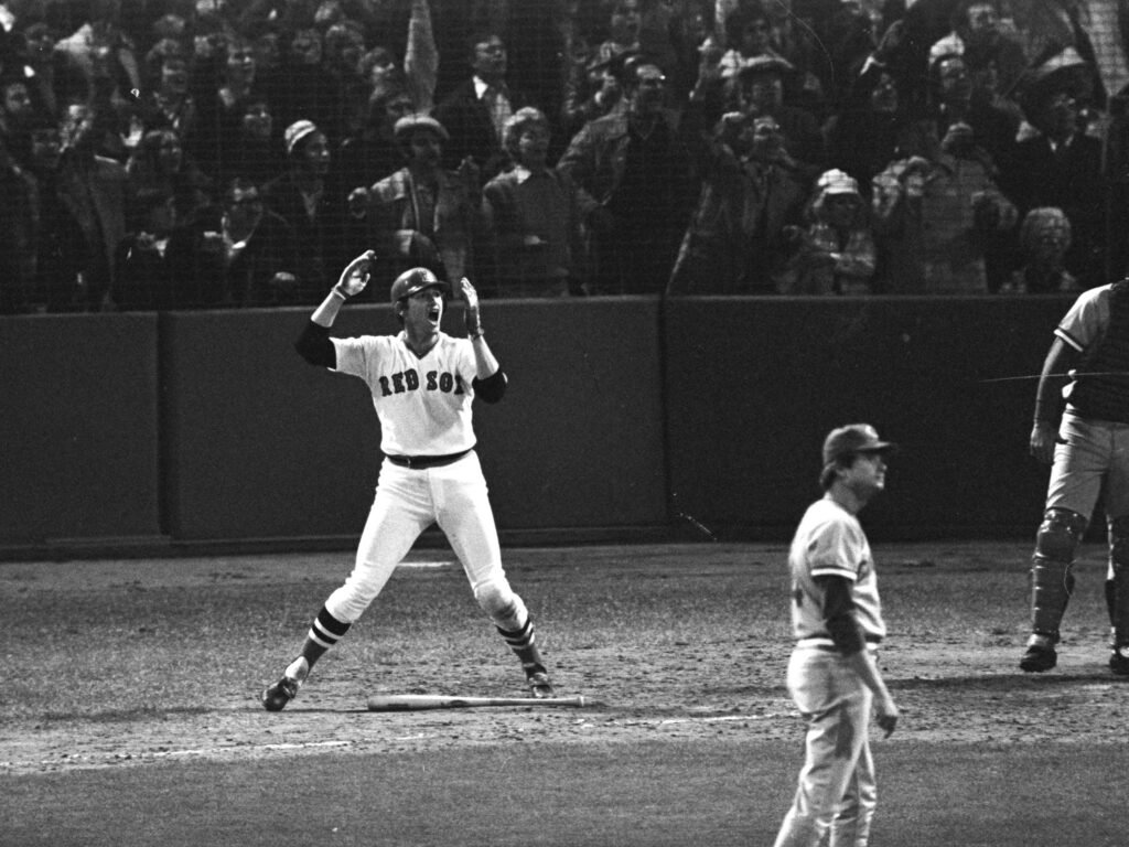 Carlton Fisk watches the flight of his home run beside the first-base line at Fenway Park.