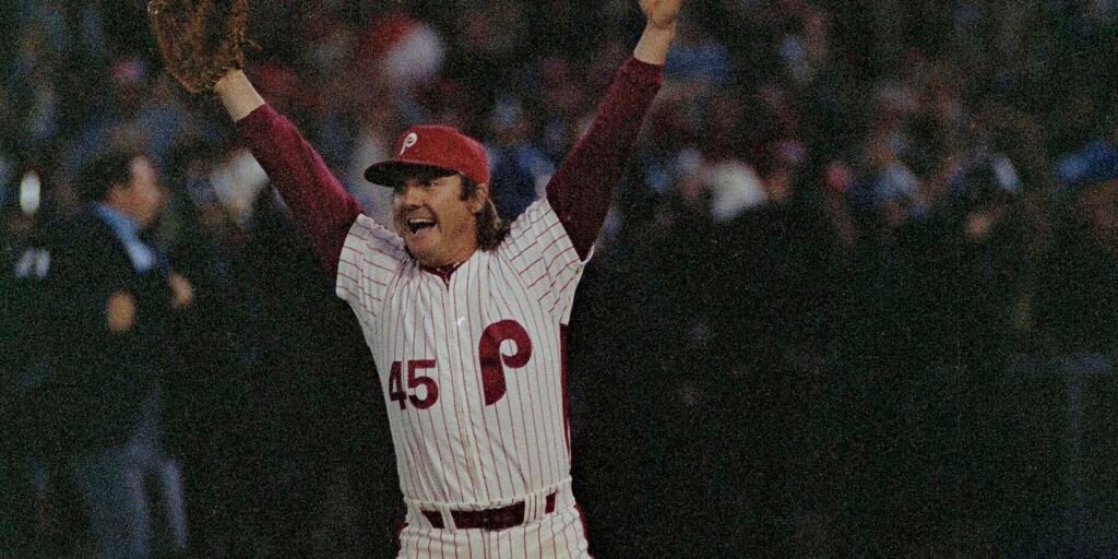 Tug McGraw raises both arms in his Phillies uniform.