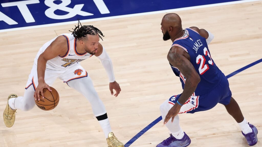 Jalen Brunson dribbles against LeBron James in a Philadelphia uniform.
