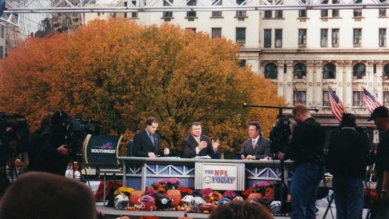 Jim Nantz, Mike Ditka and Randy Cross seated at an outdoor CBS NFL Today desk in New York in 2001.