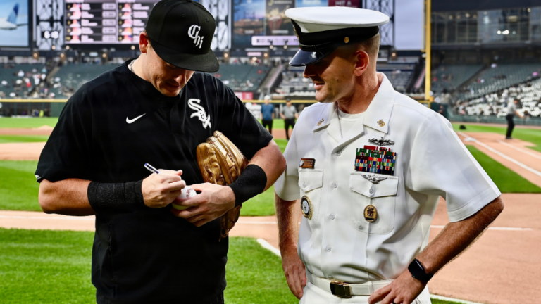 A Chicago White Sox player signs a baseball for a Navy command master chief at Rate Field in September 2026.