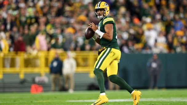 Jordan Love holds the football while looking downfield at Lambeau Field.