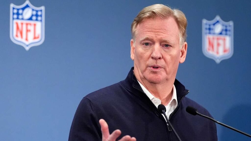 Roger Goodell speaks at a microphone with NFL logos behind him.