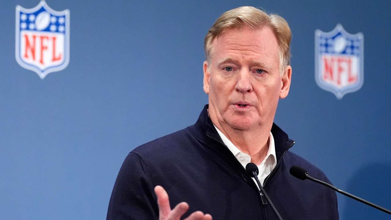 Roger Goodell speaks at a microphone with NFL logos behind him.