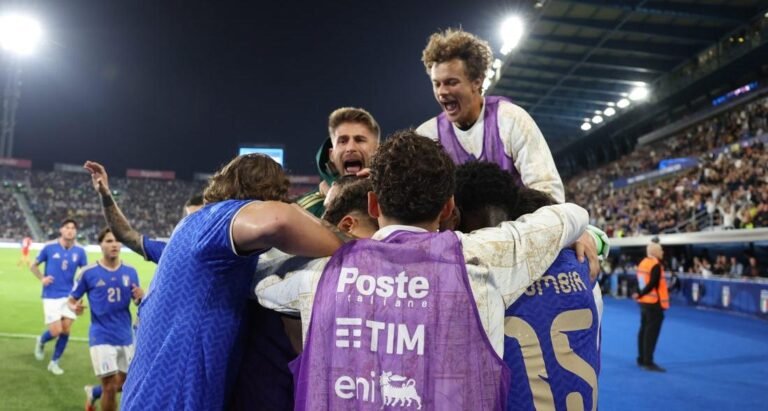Italy players and substitutes celebrate together beside the field.