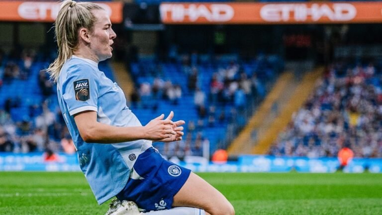 Lauren Hemp celebrates on her knees in a Manchester City uniform.