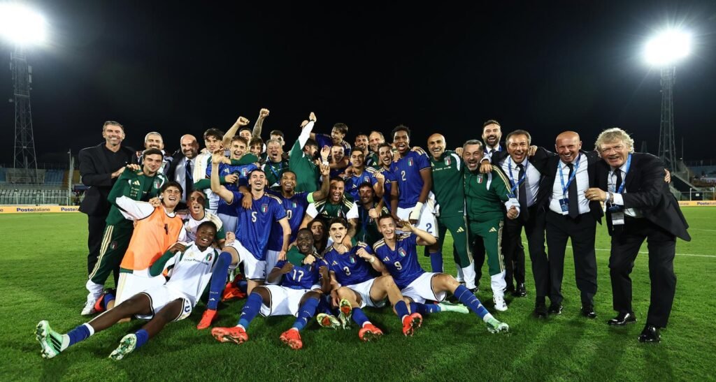 Italy’s under-21 players and staff pose together on the field.