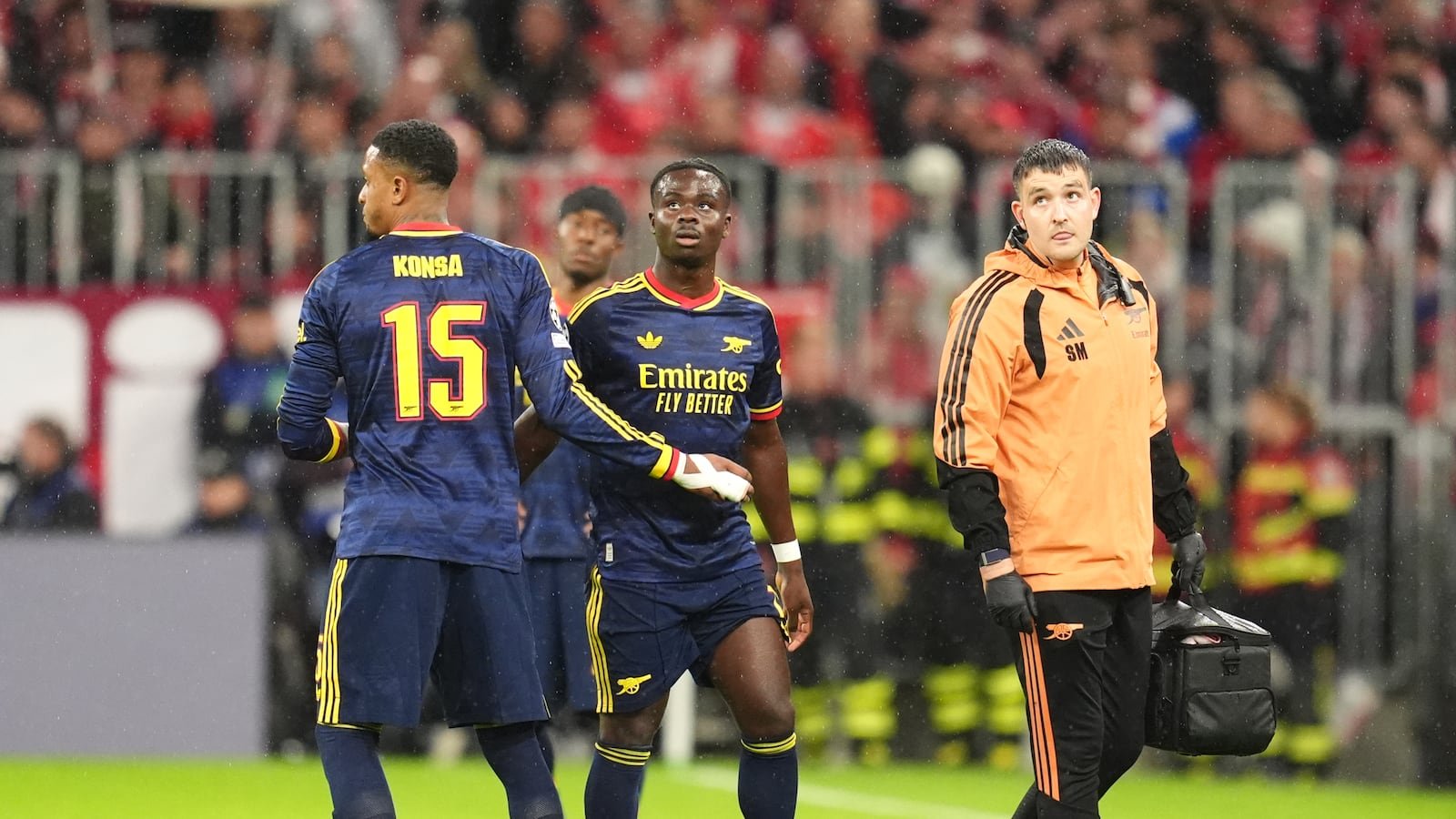 Bukayo Saka leaves the field with Arsenal medical staff at Bayern Munich