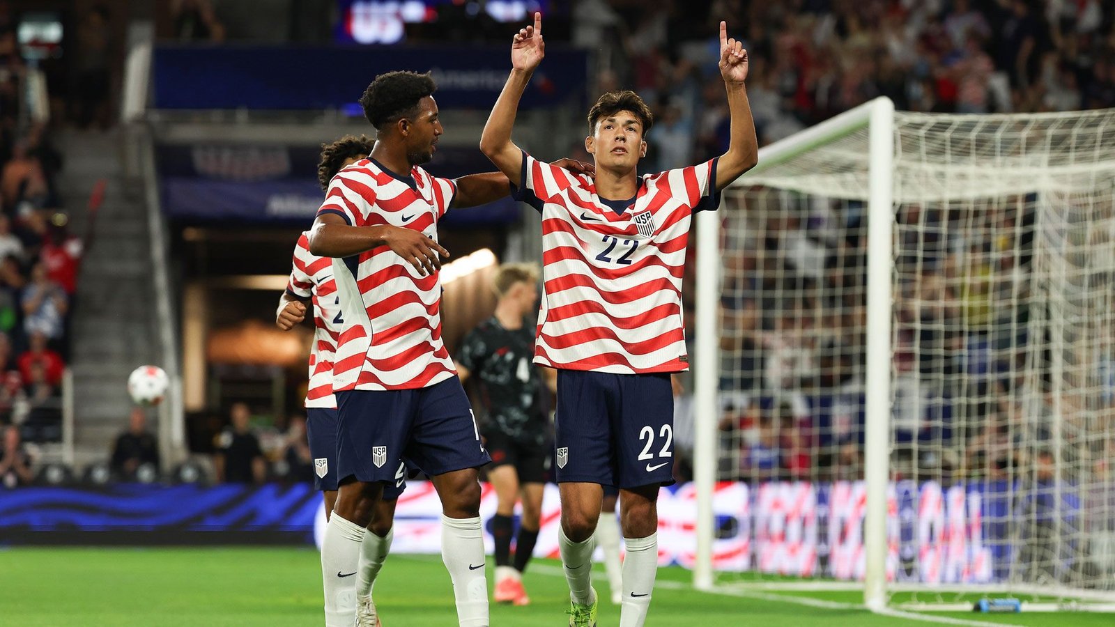 Justin Ellis raises both arms beside a U.S. teammate after scoring against Canada.