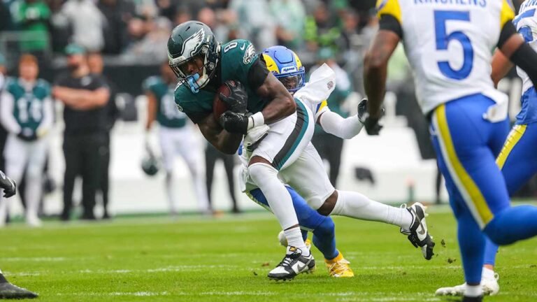 Tank Bigsby holds the football as a Rams defender tackles him.