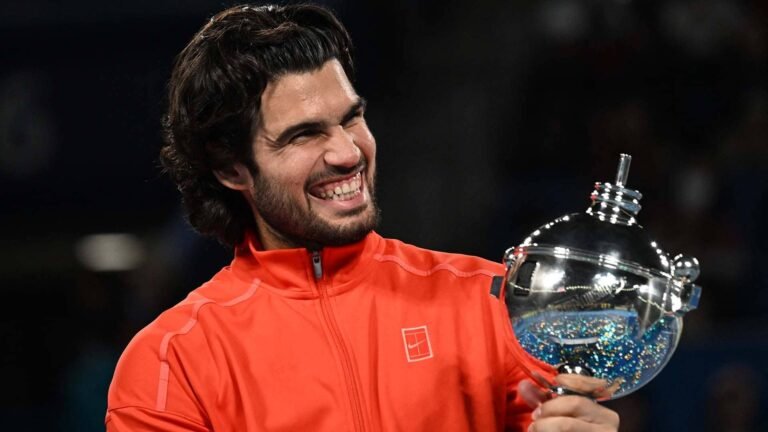 Carlos Alcaraz smiling while holding the Tokyo championship trophy.