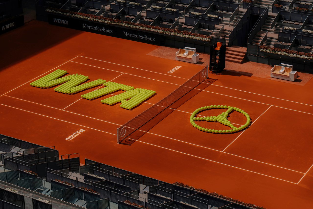 A tennis-ball installation forms WTA and Mercedes-Benz branding on the clay court in Madrid in April 2026.
