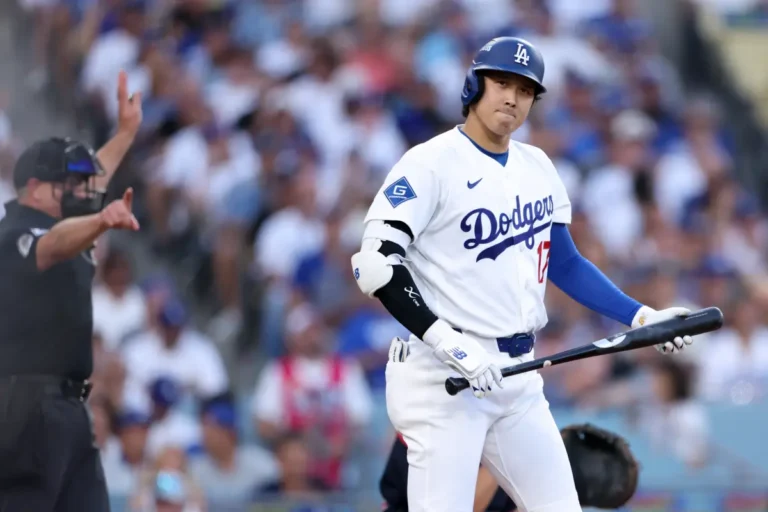 Shohei Ohtani holding his bat beside the home-plate umpire in NLDS Game 2.