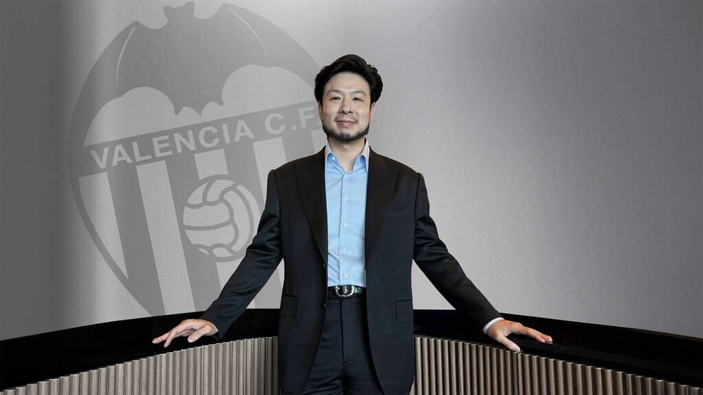 Valencia CF president Kiat Lim standing in front of the club crest.