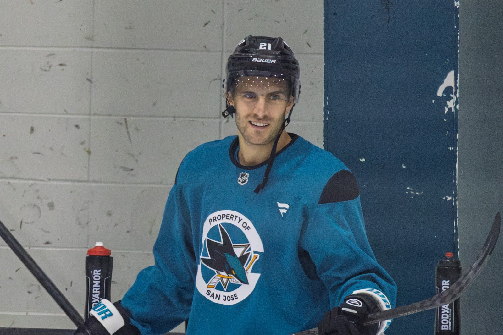 Alexander Wennberg smiles in a Sharks practice jersey while holding his stick.