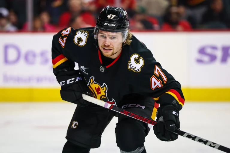 Connor Zary wears a black Calgary Flames jersey and helmet during a game.