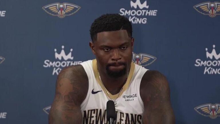 Zion Williamson in a white Pelicans jersey speaking into a microphone at media day.